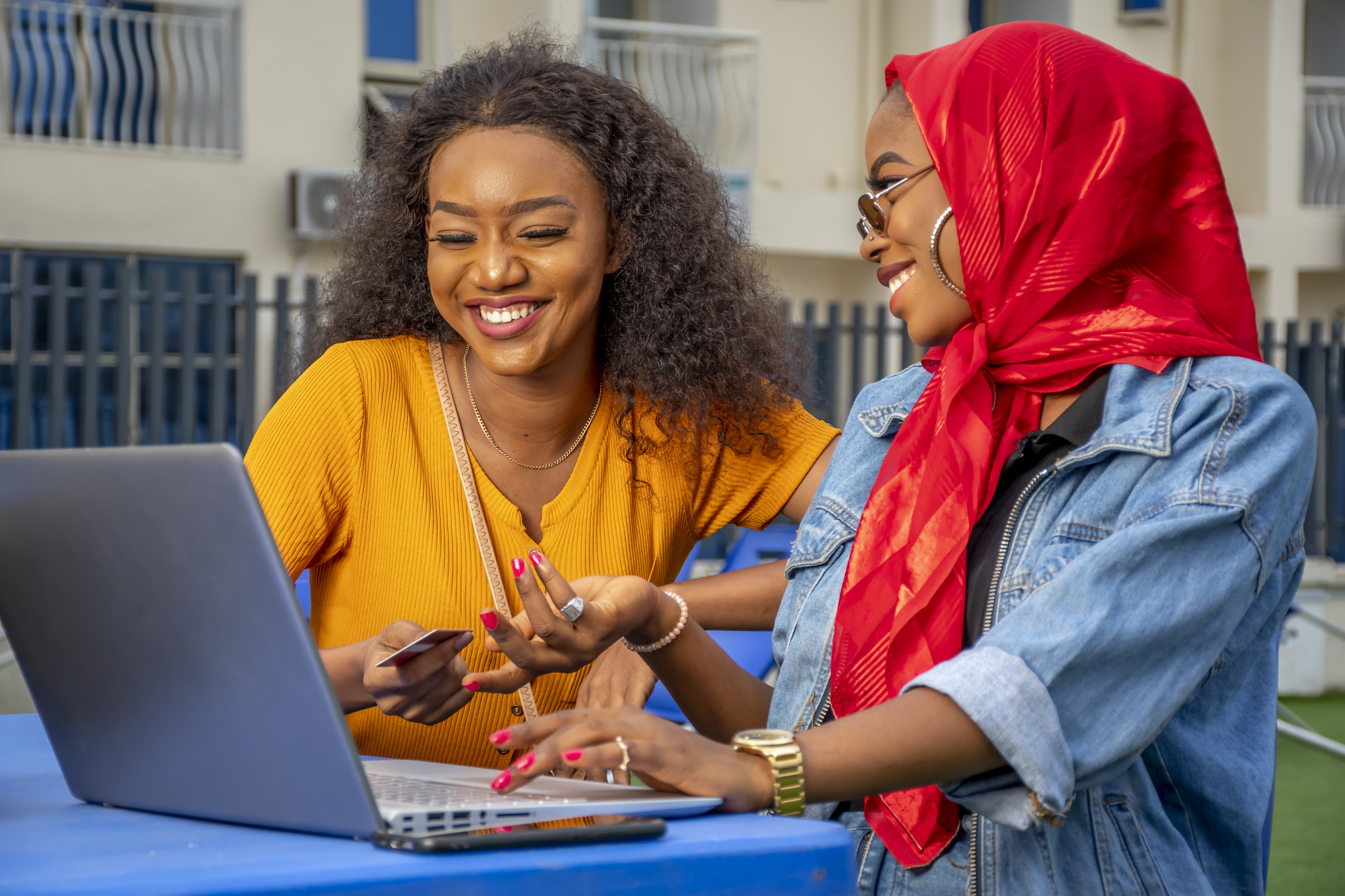 Two cheerful young African ladies with laptop